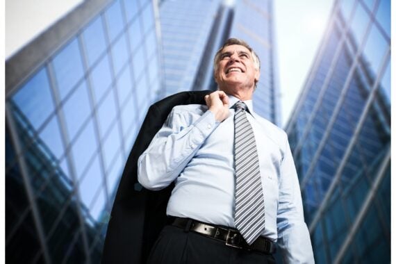Confident mature businessman in front of tall downtown buildings