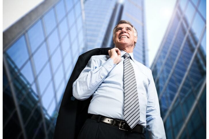 Confident mature businessman in front of tall downtown buildings