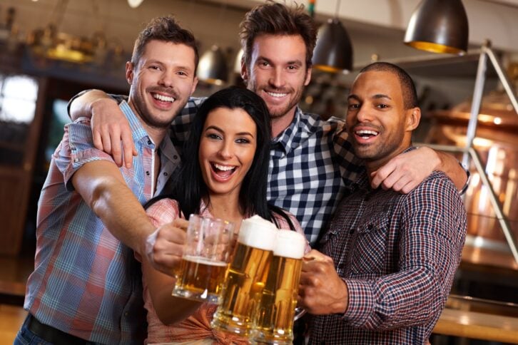 happy young friends drinking beer at pub, laughing, clinking glasses
