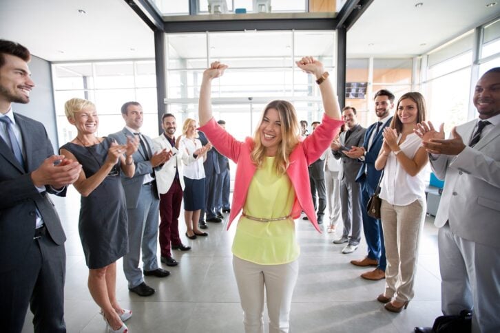 Group of employees congratulating a happy female leader