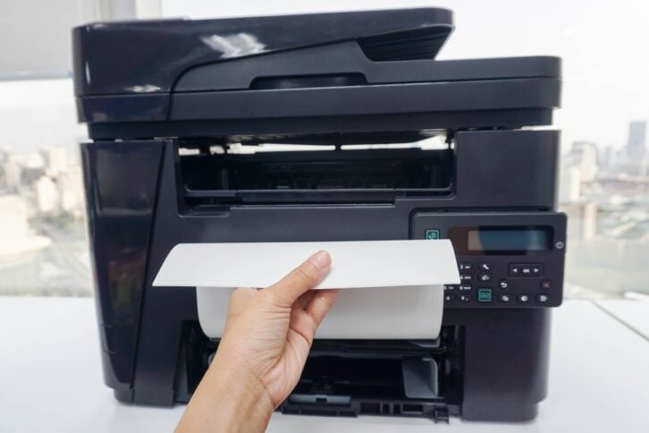 woman officer pull printed business documents from multi functional office printer