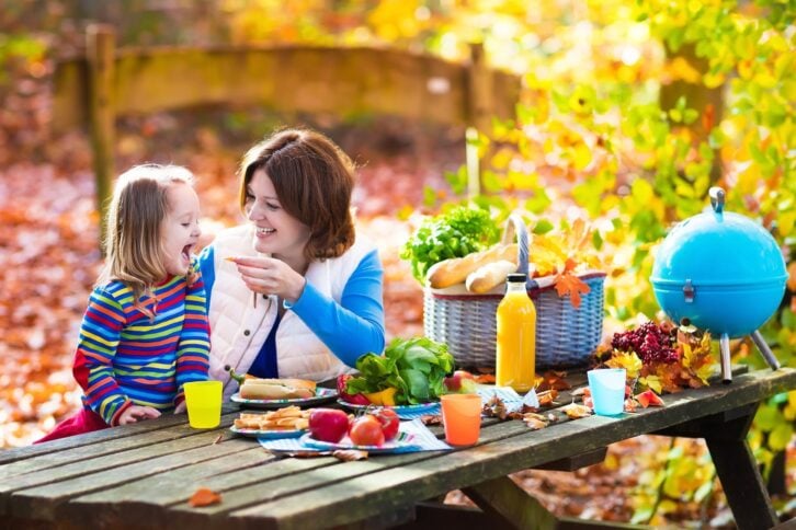 mother and daughter eating picnic outside in autumn