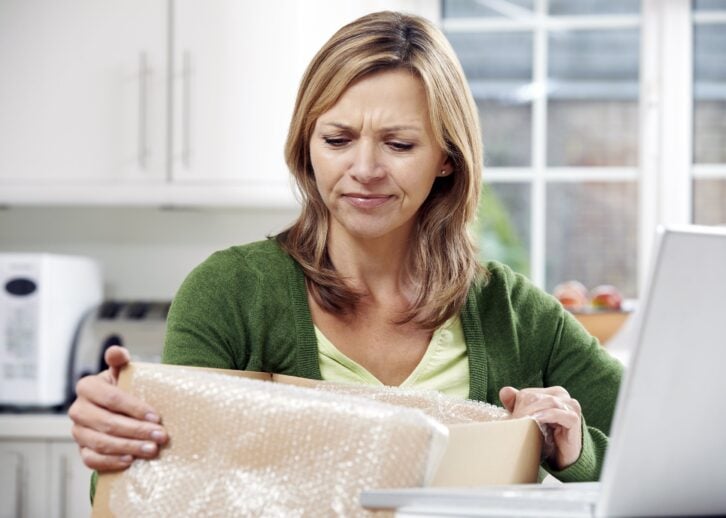 disappointed woman unpacking online purchase at home