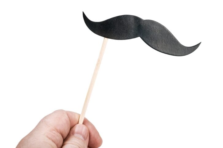 mustache of paper in his hand on a stick
