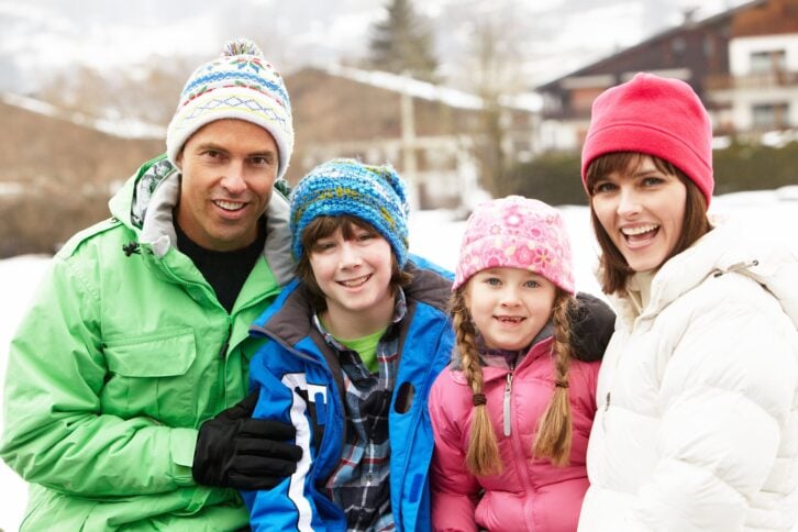 family wearing winter clothes in snowy landscape