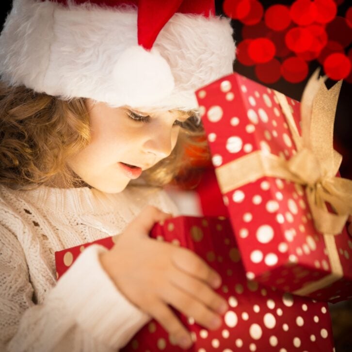 happy child in Santa hat opening Christmas gift box