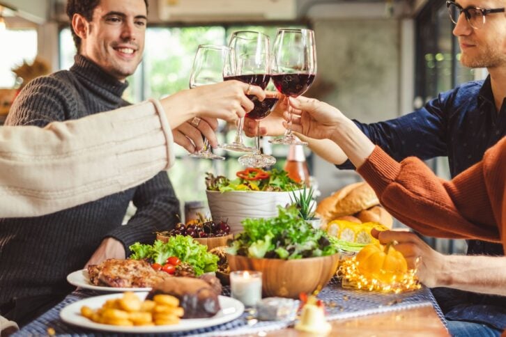 young people celebrating Christmas party dinner with clinking glass of wine