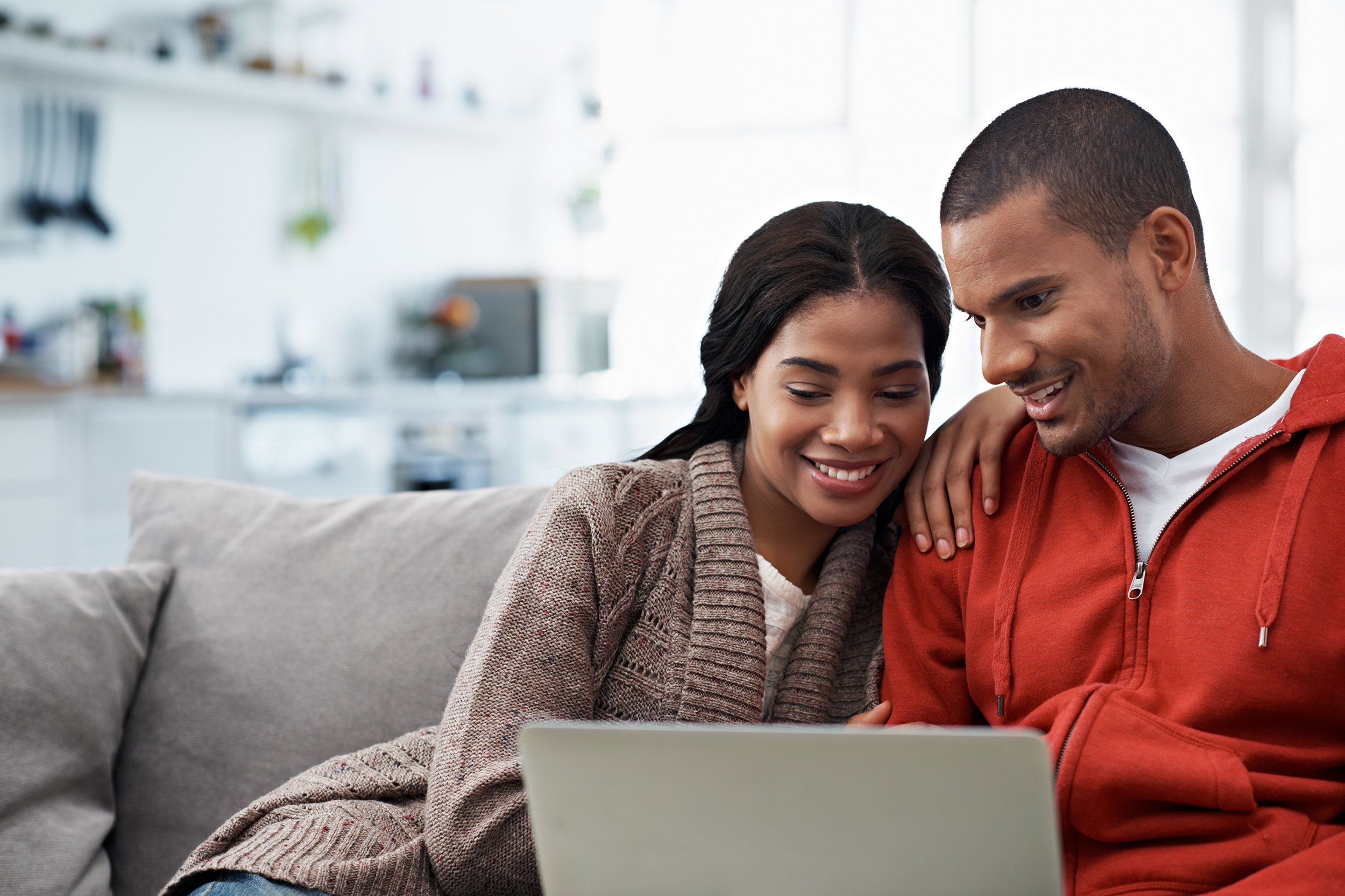 African American couple on laptop while sitting on couch