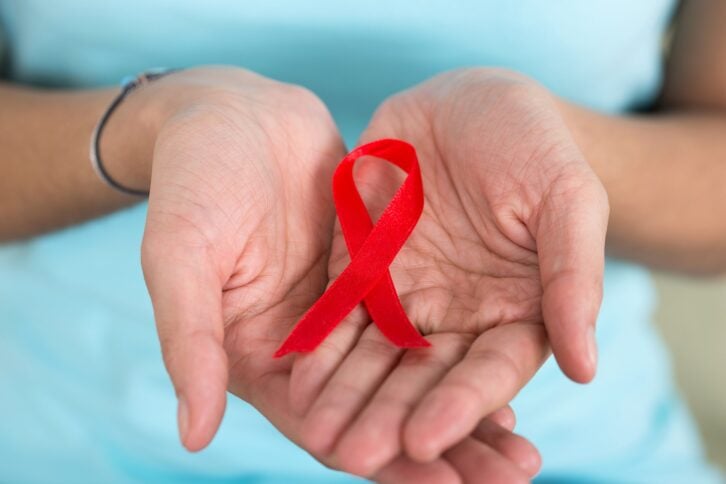 Closeup of woman's hands holding a red ribbon for World Aids Day