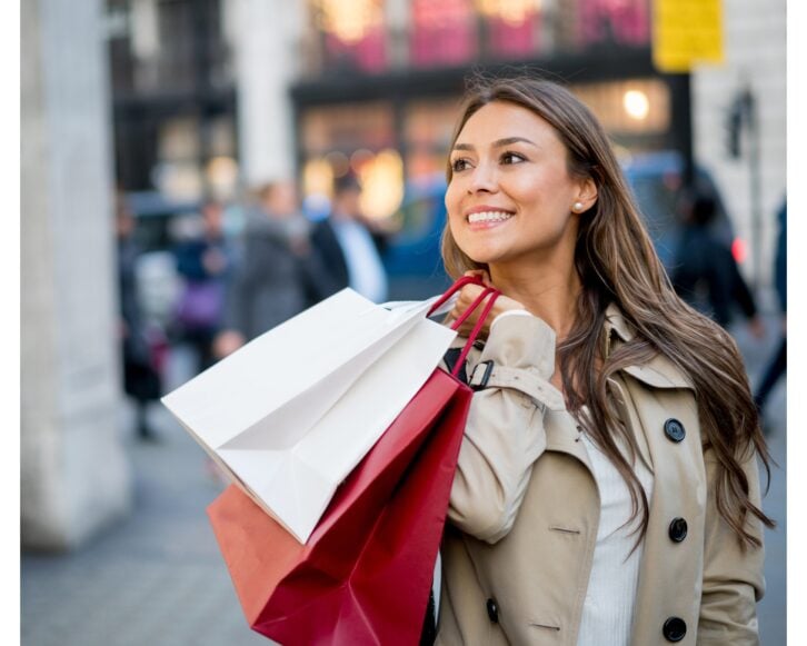 Woman smiling and shopping outside holding shopping bags