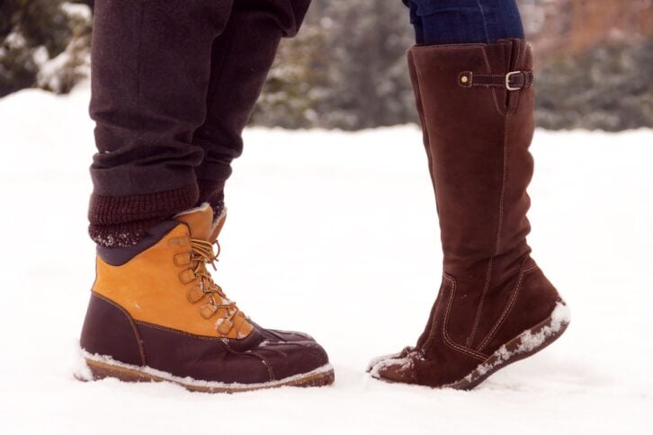 Closeup of man and woman's boots in the snow
