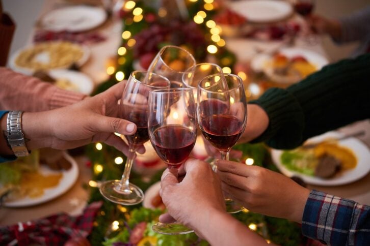 people at dinner table for the holidays, toasting glasses with red wine