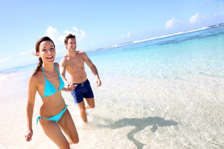 smiling young couple holding hands on the beach
