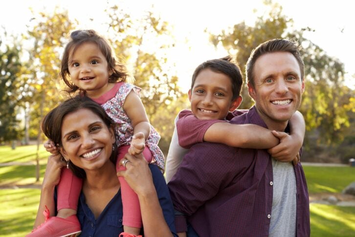 Happy family smiling at camera outside