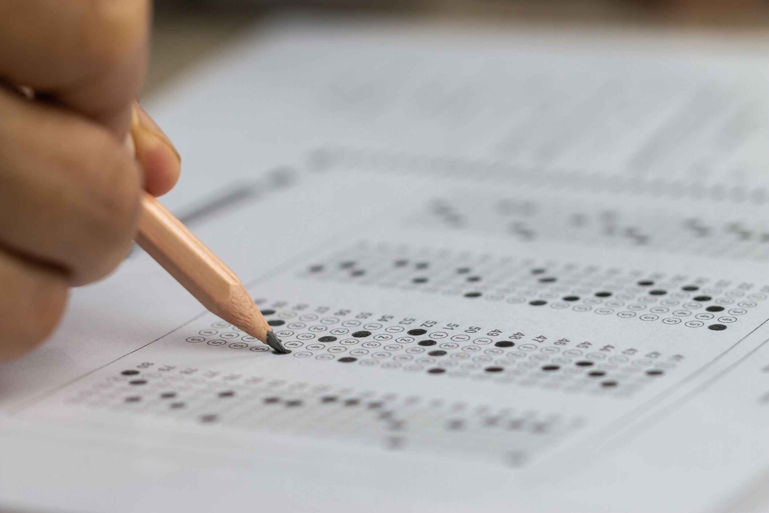 hand holding pencil for testing exams writing answer sheet for taking fill in admission exam