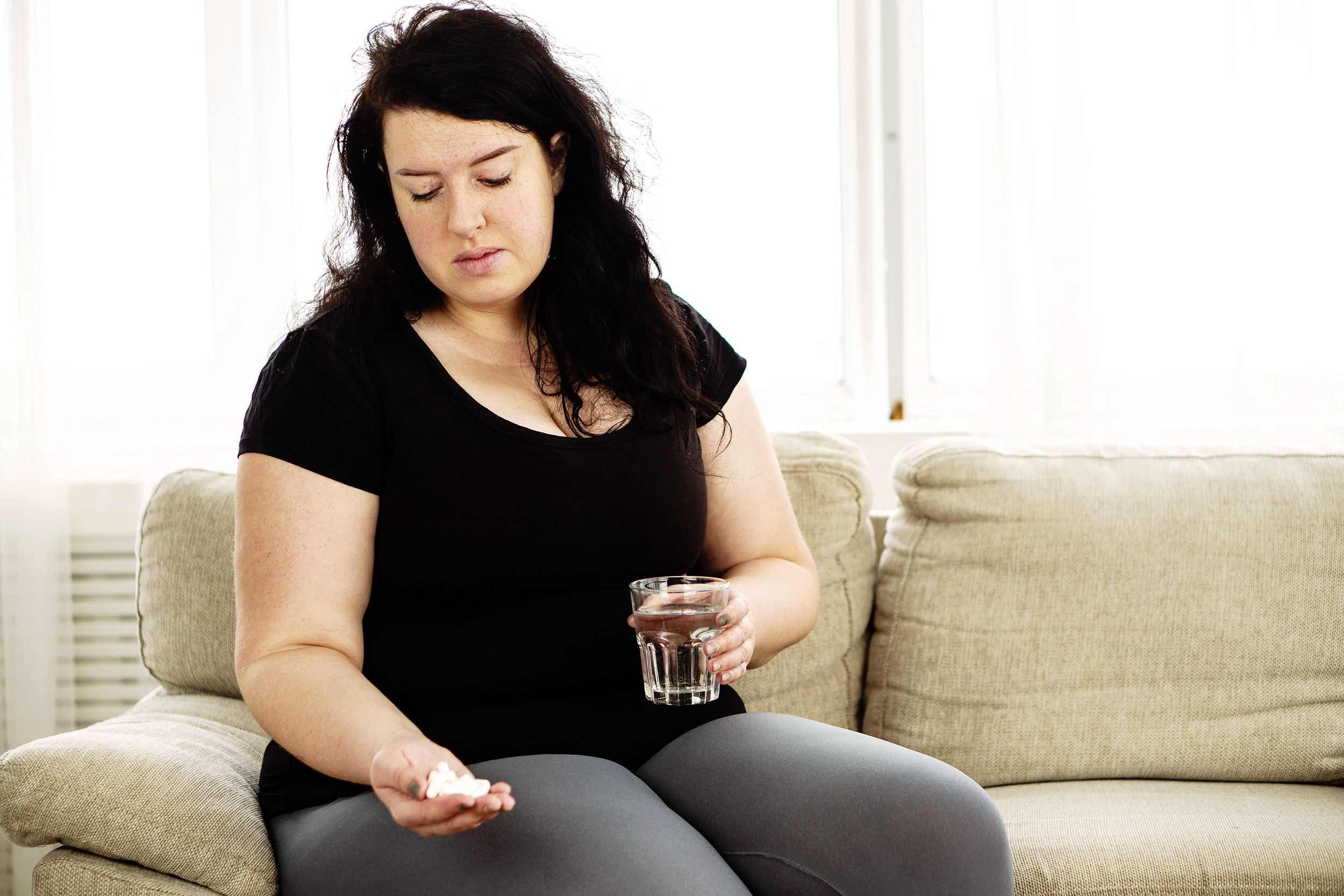 overweight woman taking pills for weight loss