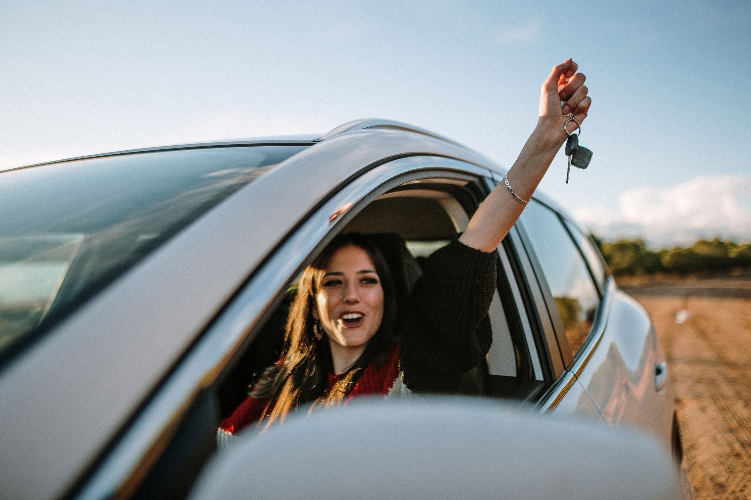 young woman showing the car keys through the car window