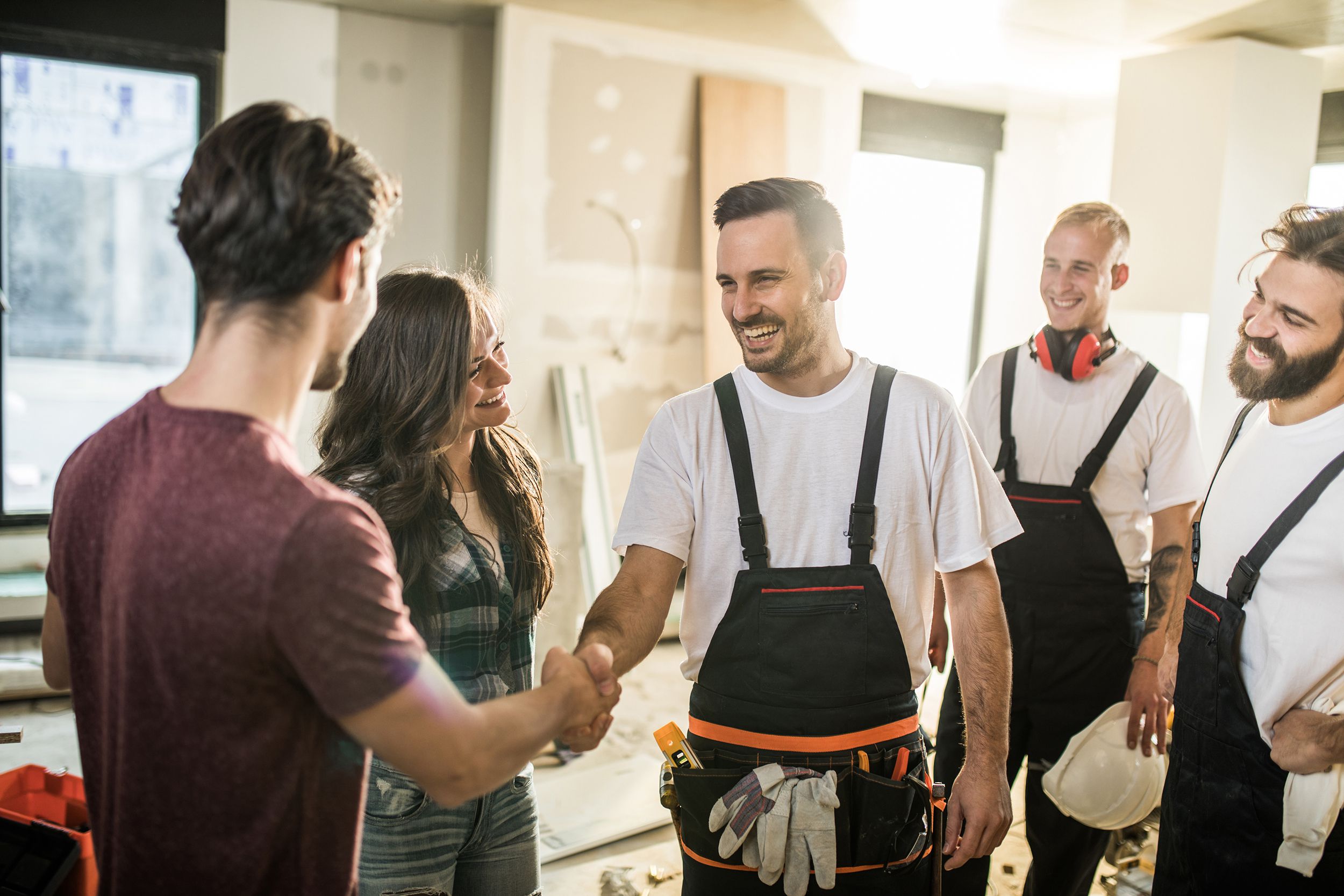 team of happy manual workers welcoming a couple to their apartment