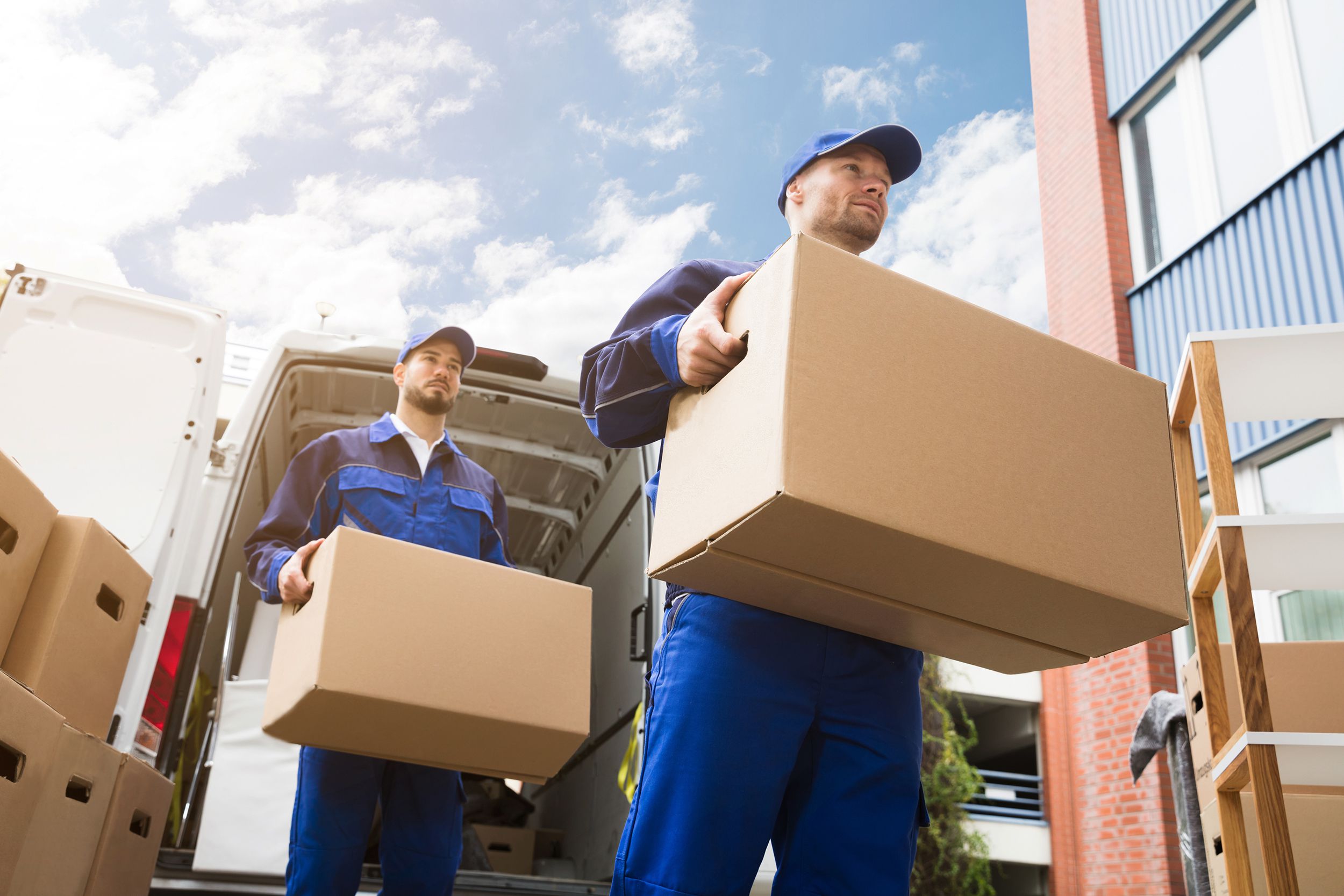 close-up of two delivery men carrying cardboard box