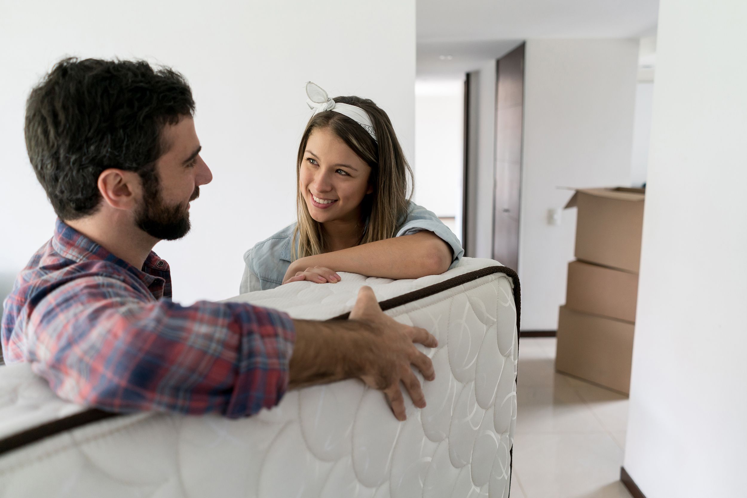 playful woman with her partner while he is moving in a matress into their new place