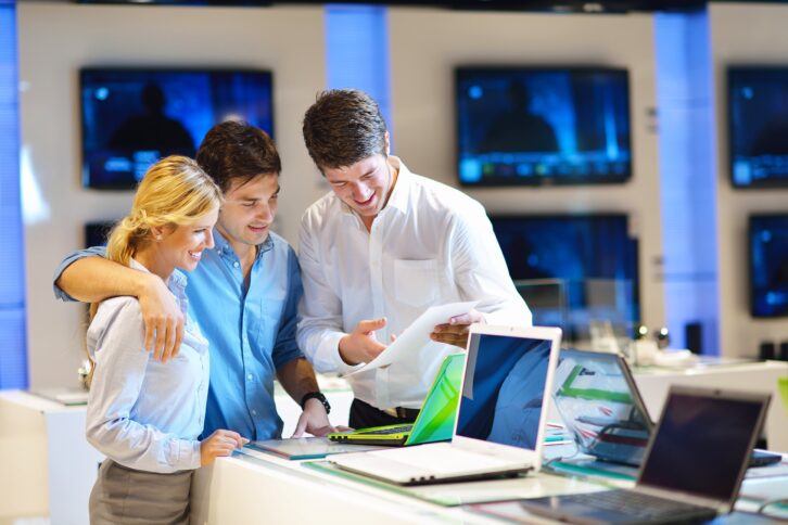 young couple in consumer electronics store looking at laptops