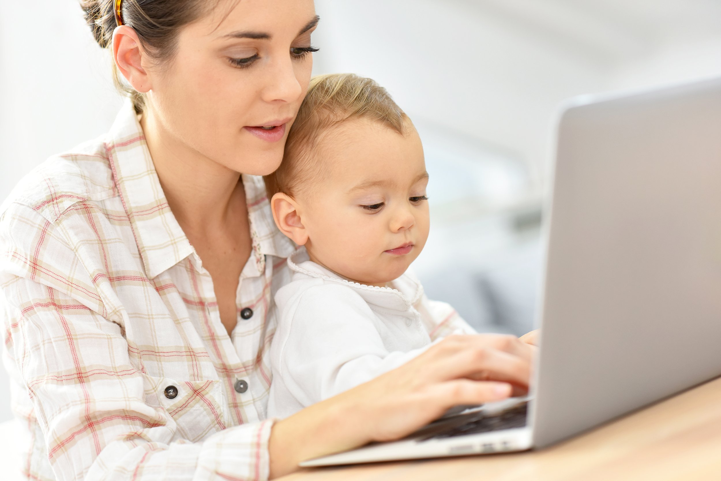 busy young businesswoman working on laptop, baby on lap