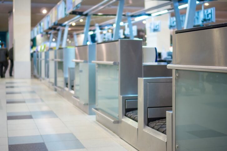 row of empty check-in desks with computers in airport