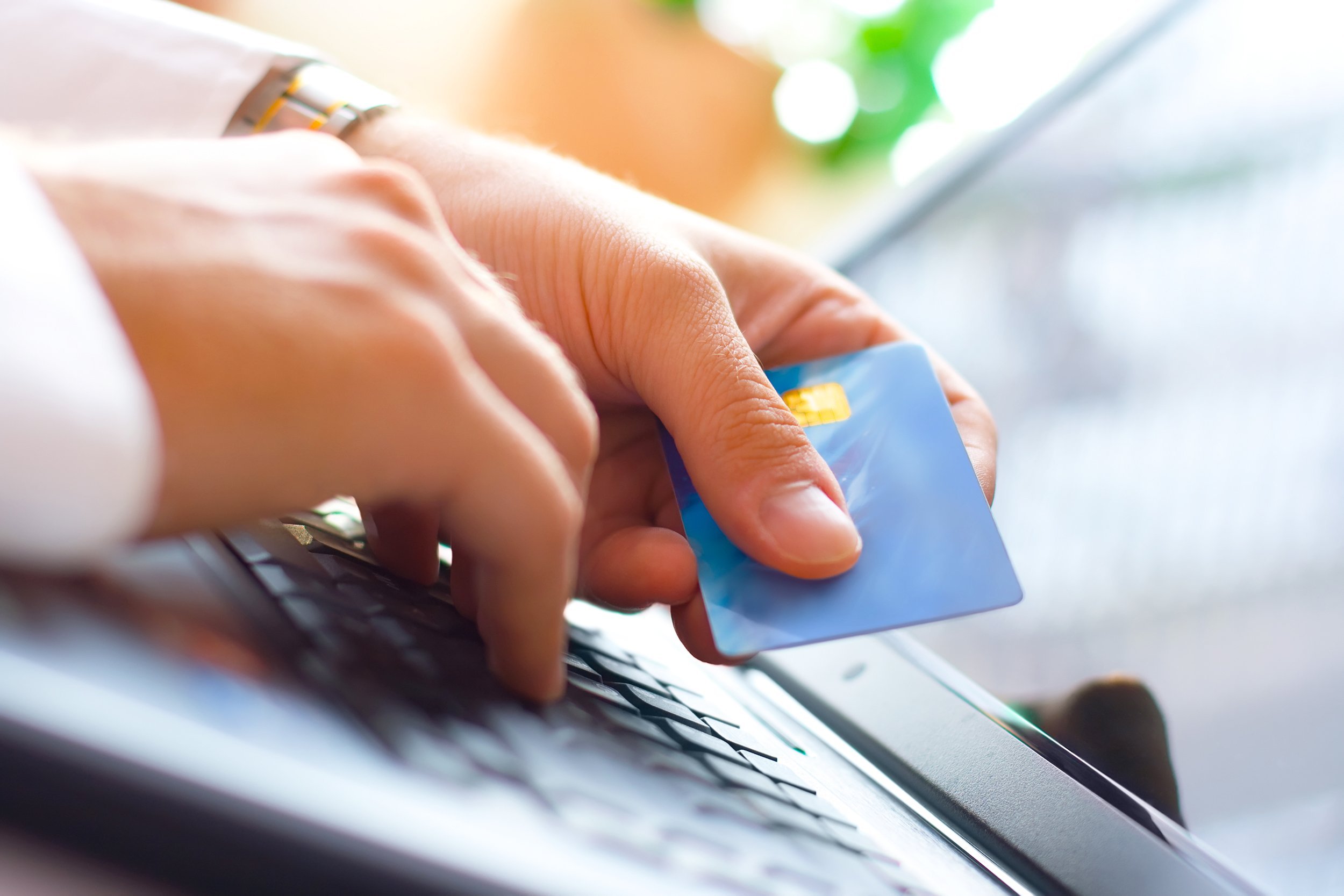 businessman holding a credit card and typing on laptop