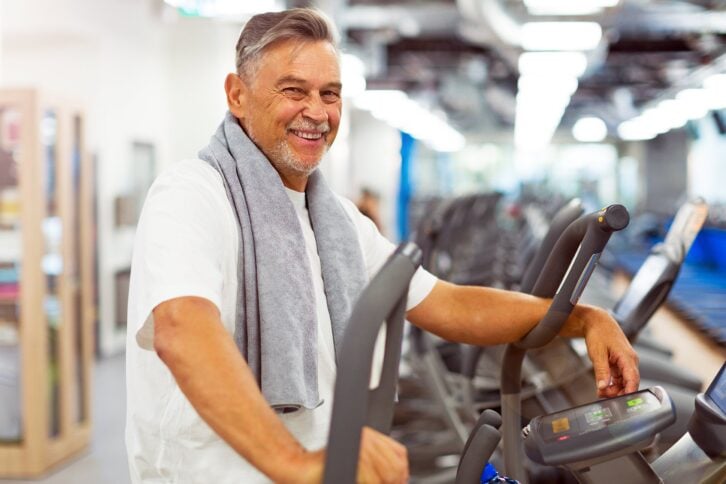 Older man at the gym with a towel around his neck