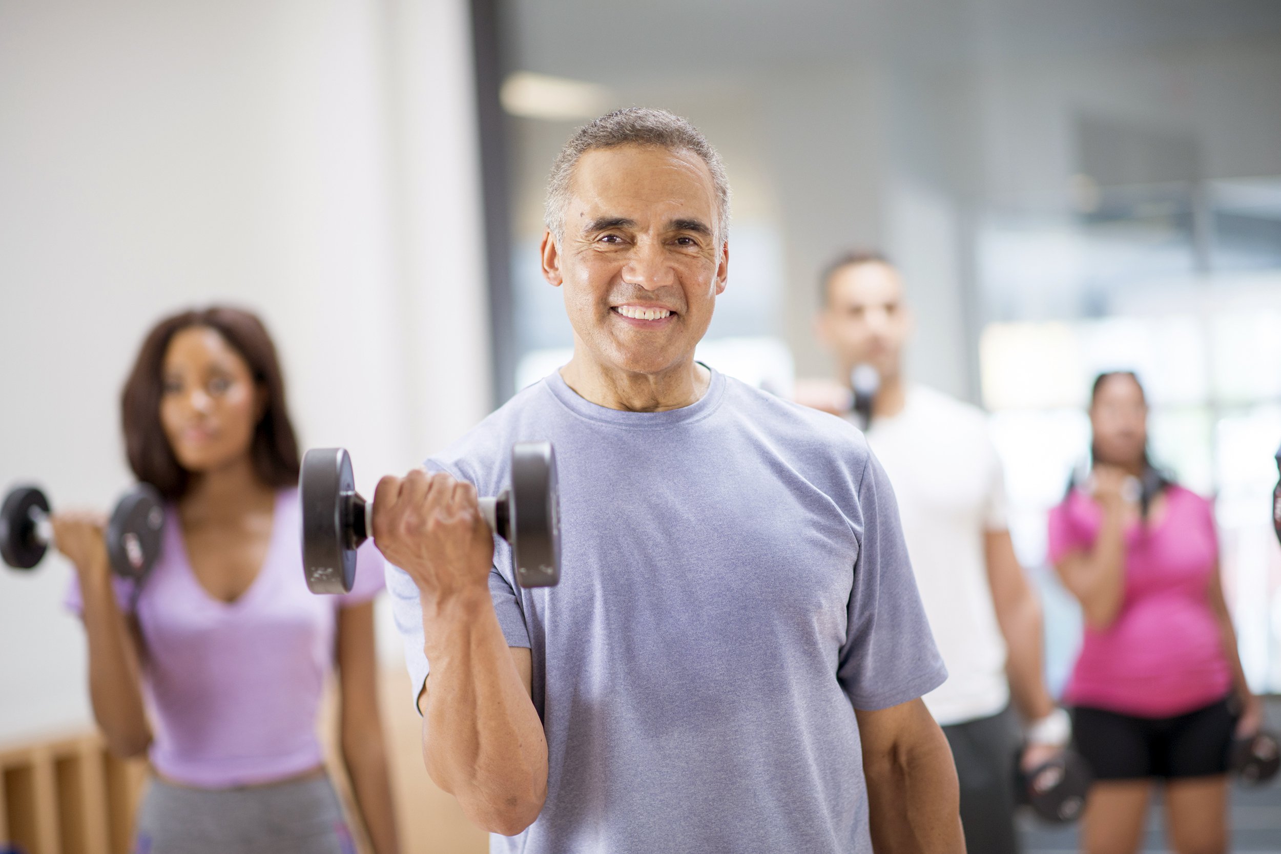 Happy man smiling at the gym with a free weight