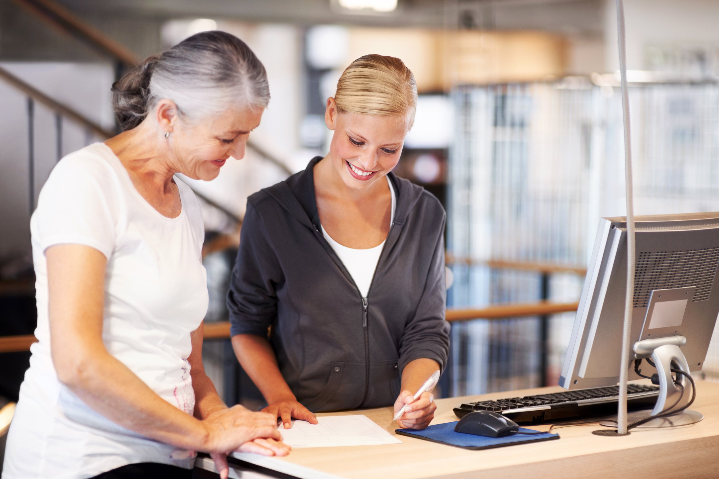 Older woman looking at gym contract with gym employee