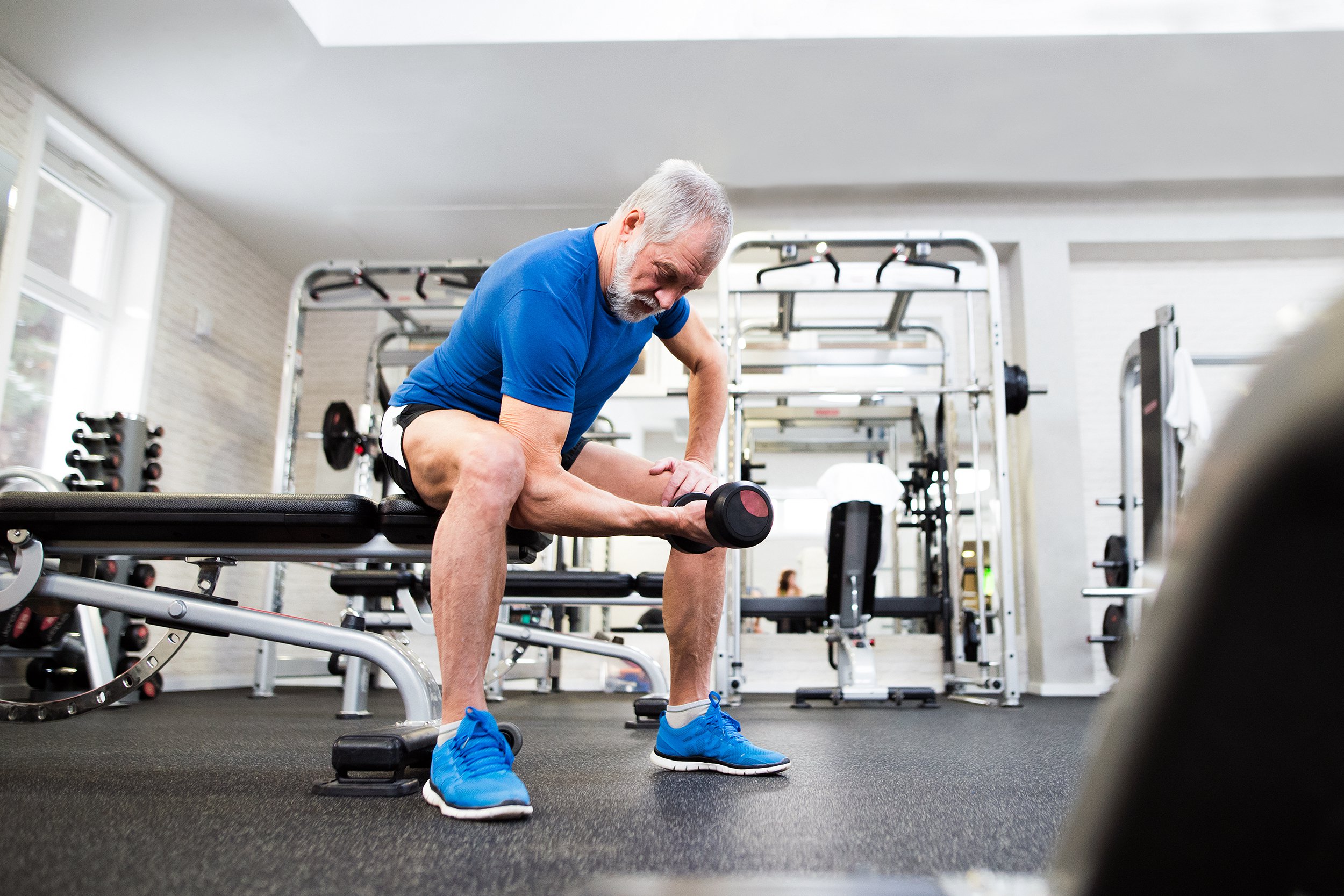 Older man lifting weights by himself at gym