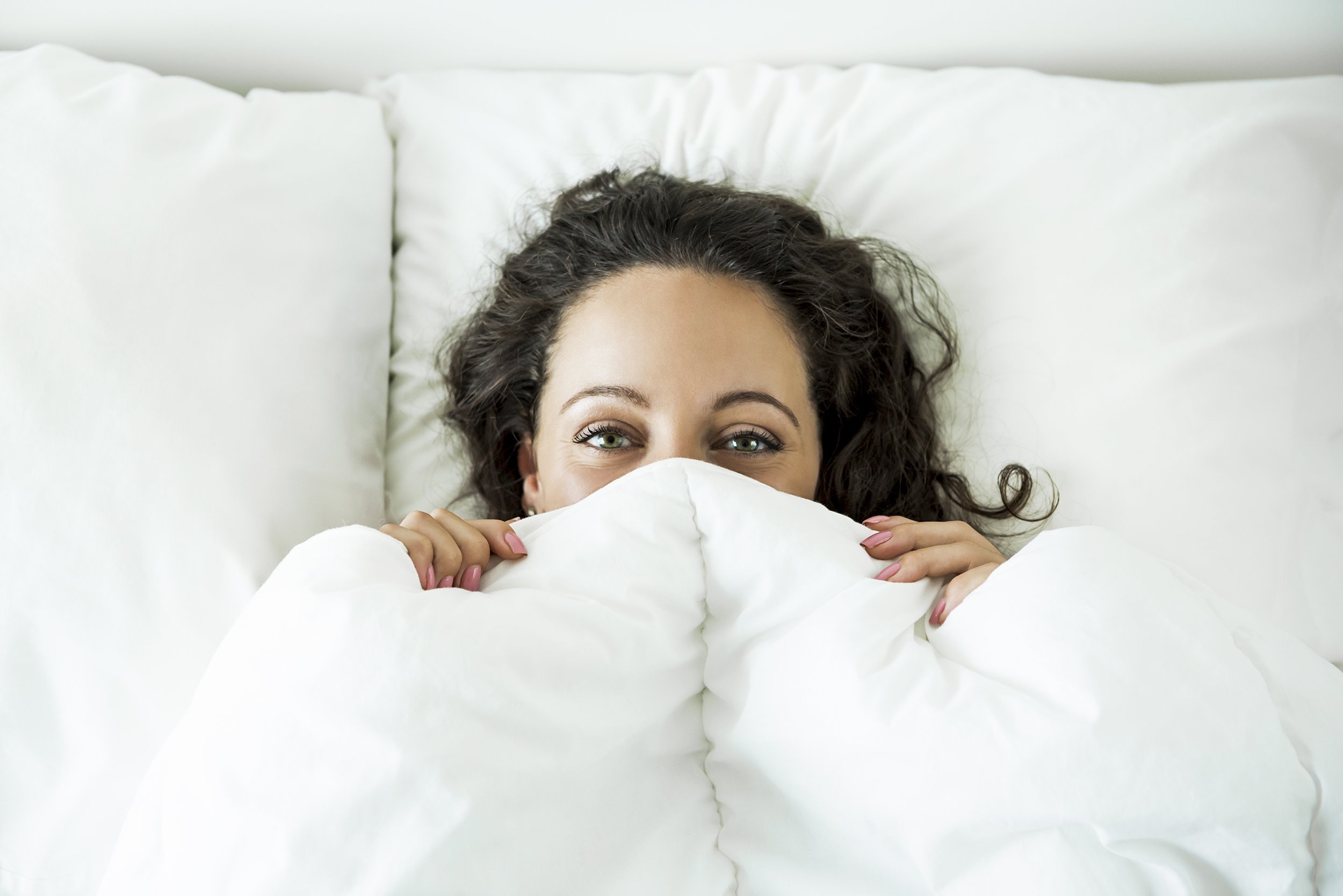 woman in the bed in covers and smiling