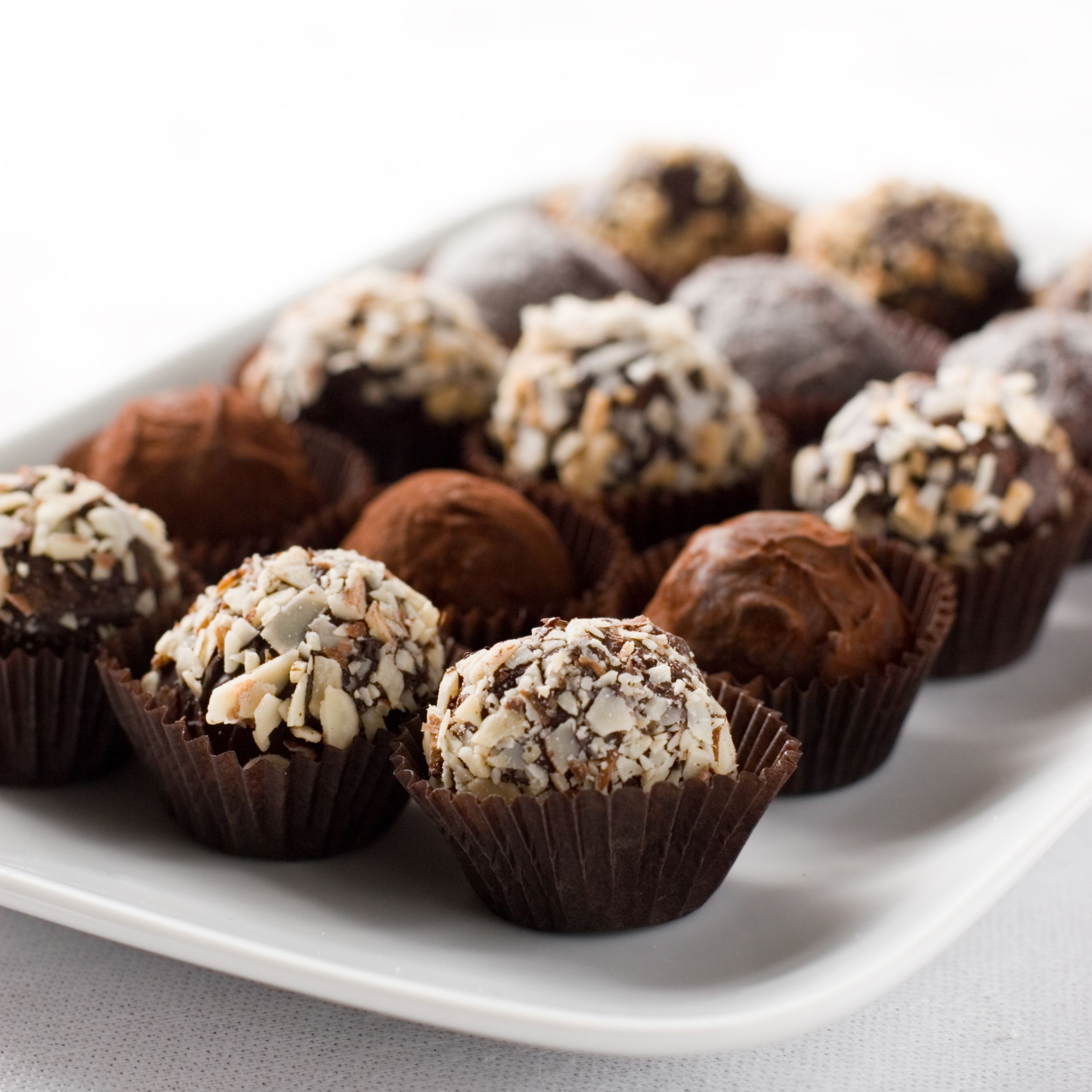 fifteen chocolate Godiva truffles laid out on white plate