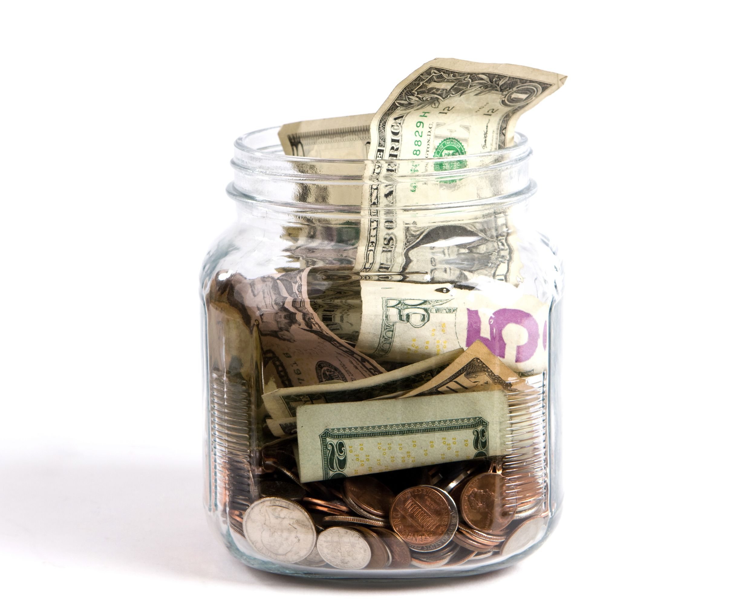 US dollars and coins fill a glass tip jar