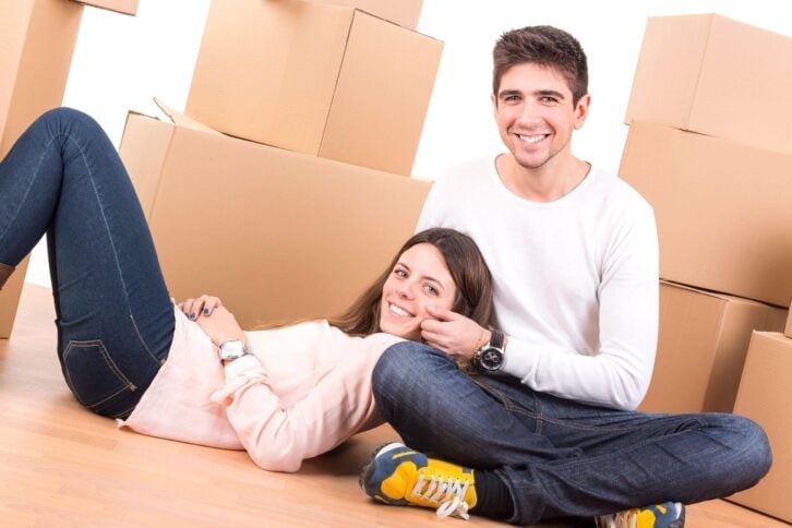 happy couple with boxes moving into new home apartment
