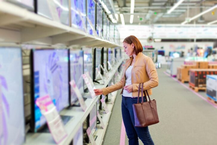 Woman shopping in an electronics store and looking at tvs