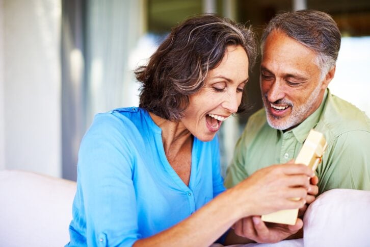Happy mature woman opening a gift from her husband