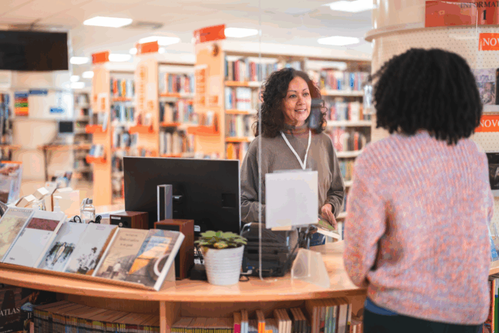Woman Talking to Librarian at the Desk in a Public Library