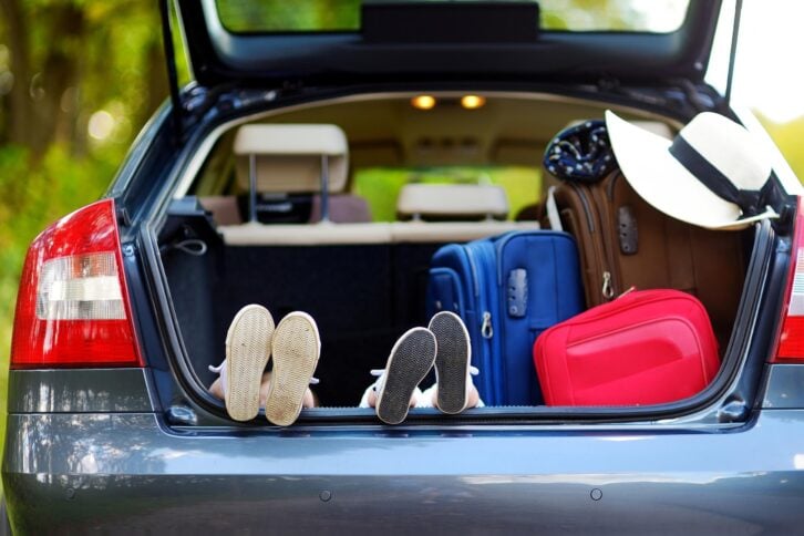 two sets of kids' feet in a car of trunk during vacation