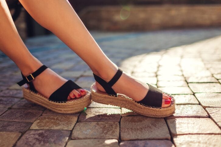 stylish woman wearing black summer shoes with straw sole outdoors