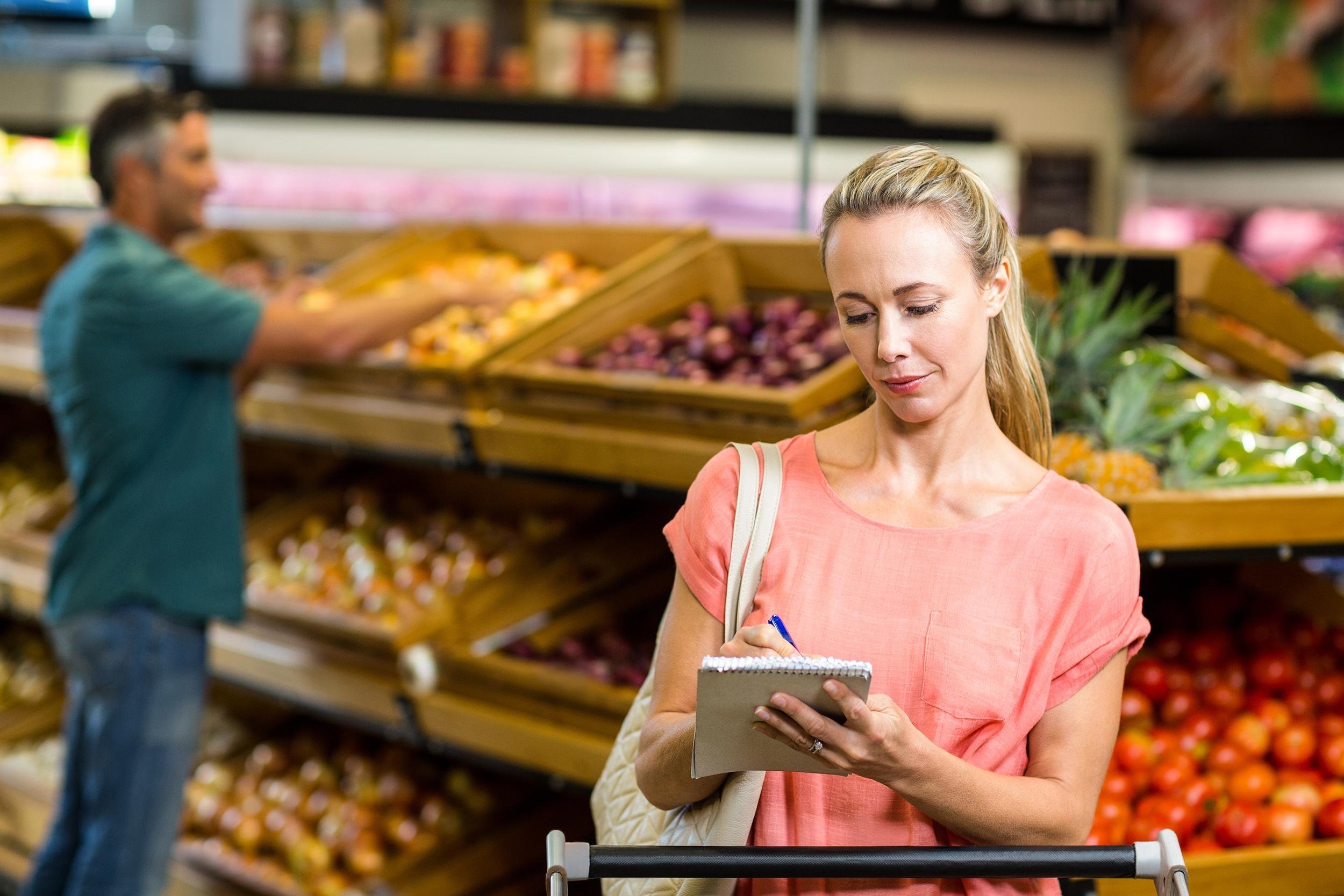 woman writing list in grocery store