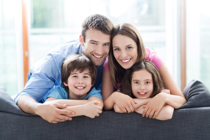 family smiling together on top of a sofa