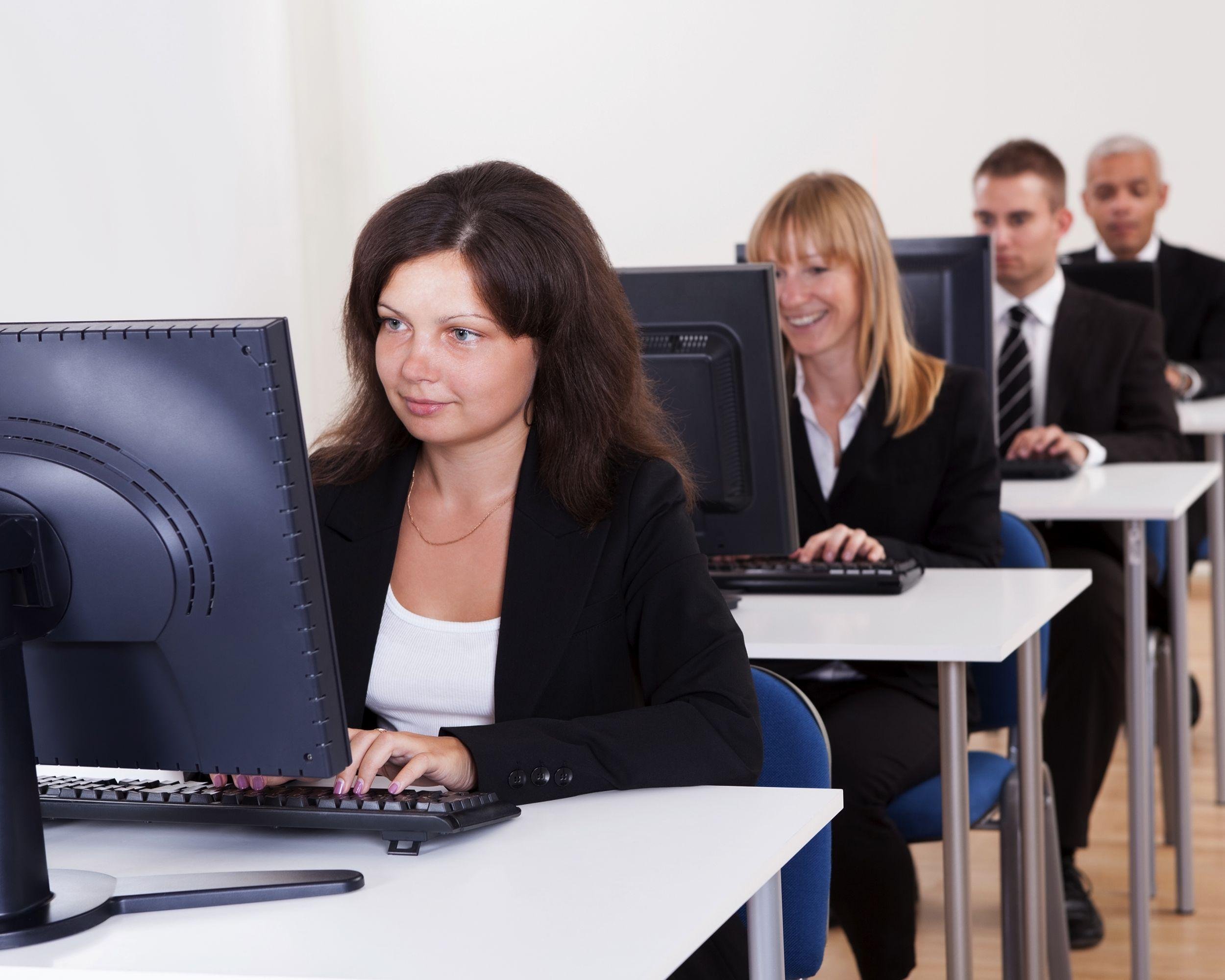 business people working in a support centre sitting at desks in front of computer monitors