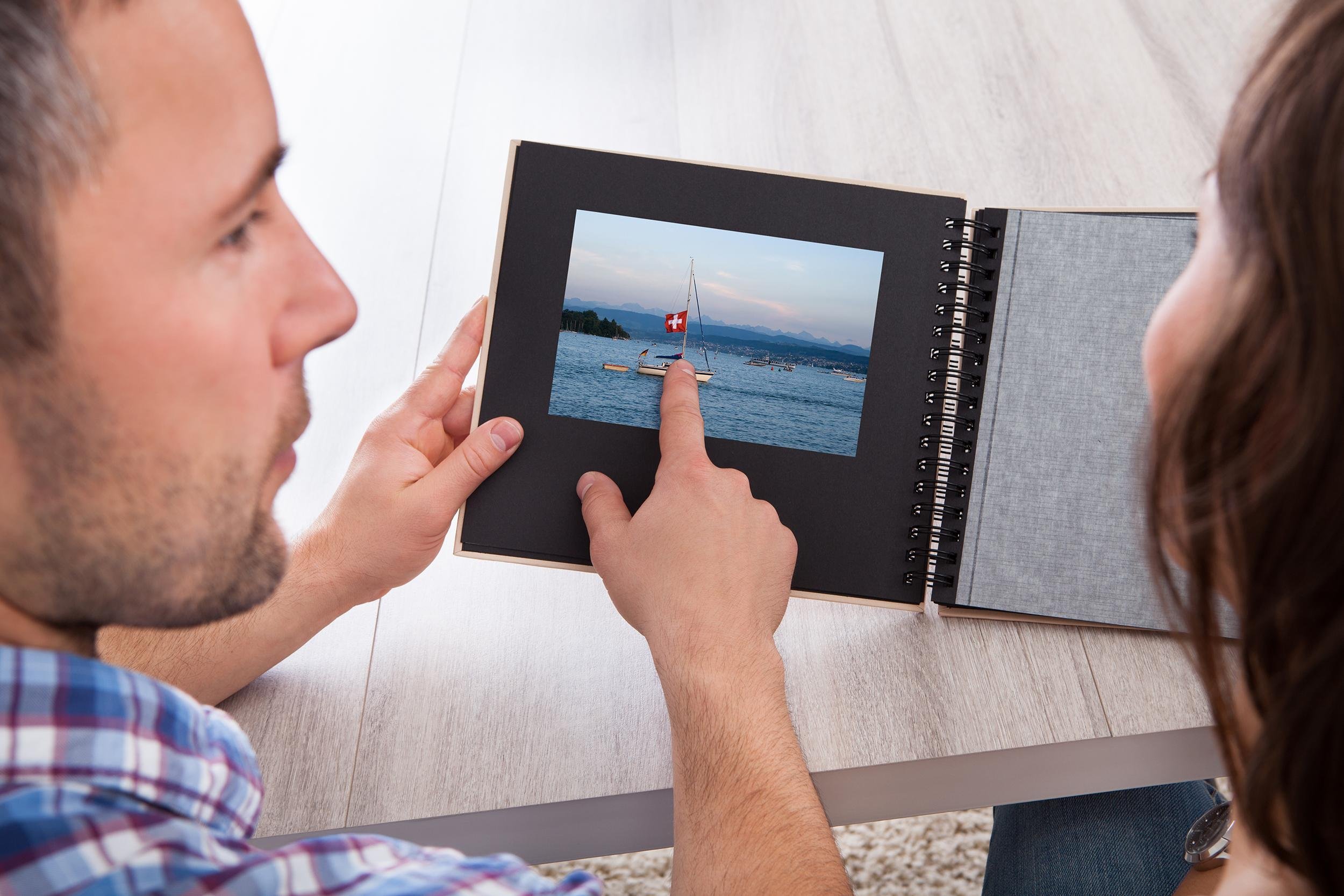 woman looking at photo album pointed by man