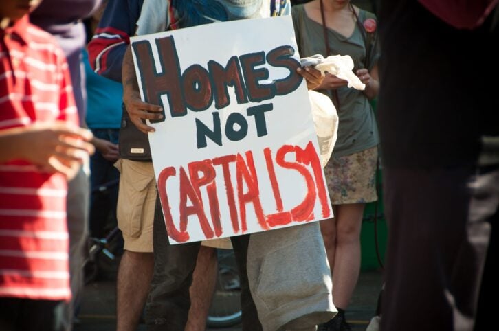 Person holds sign that reads "Homes Not Capitalism" for 6th annual Women's Housing March in Vancouver, BC, in 2012