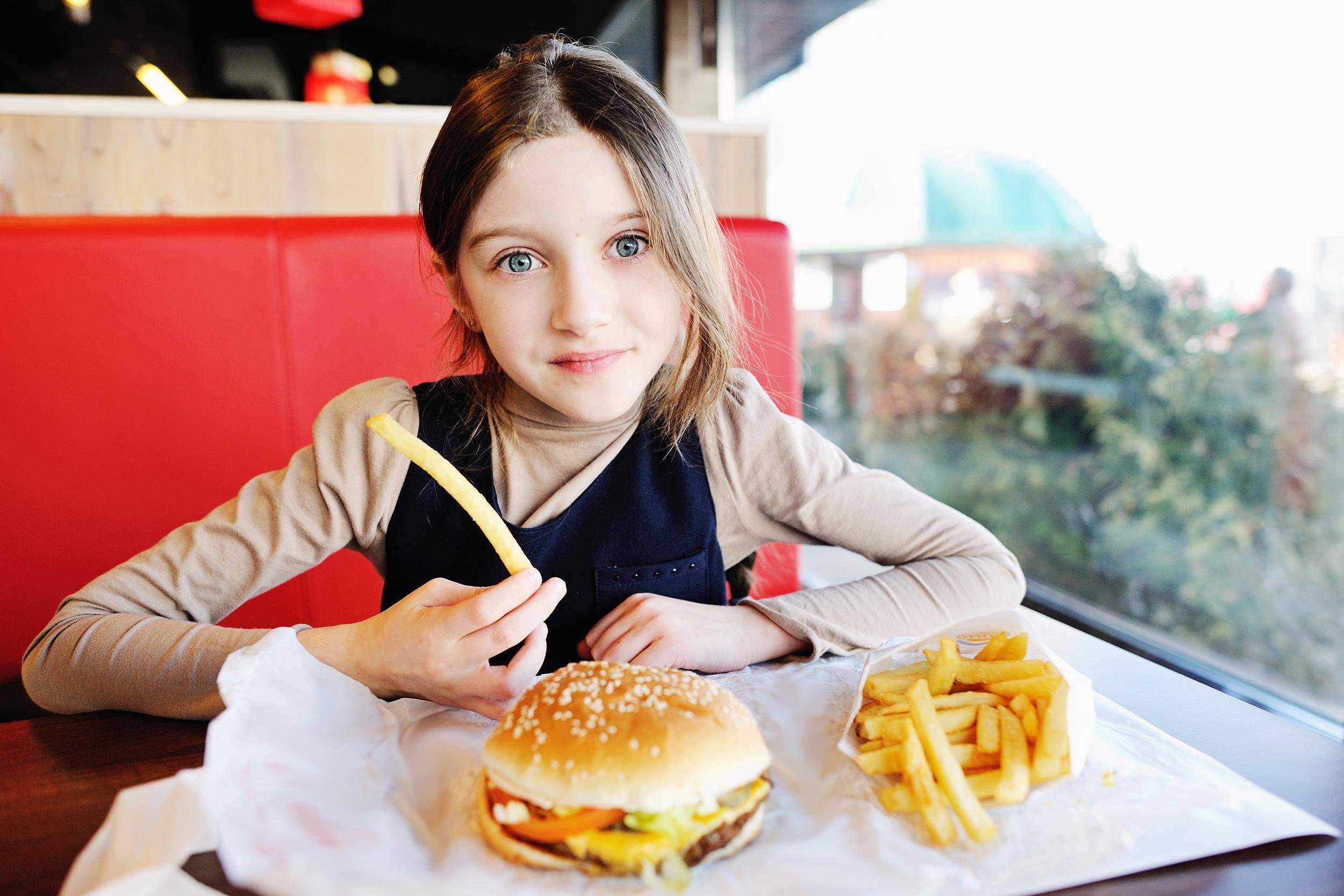 child eating burger at fast food place
