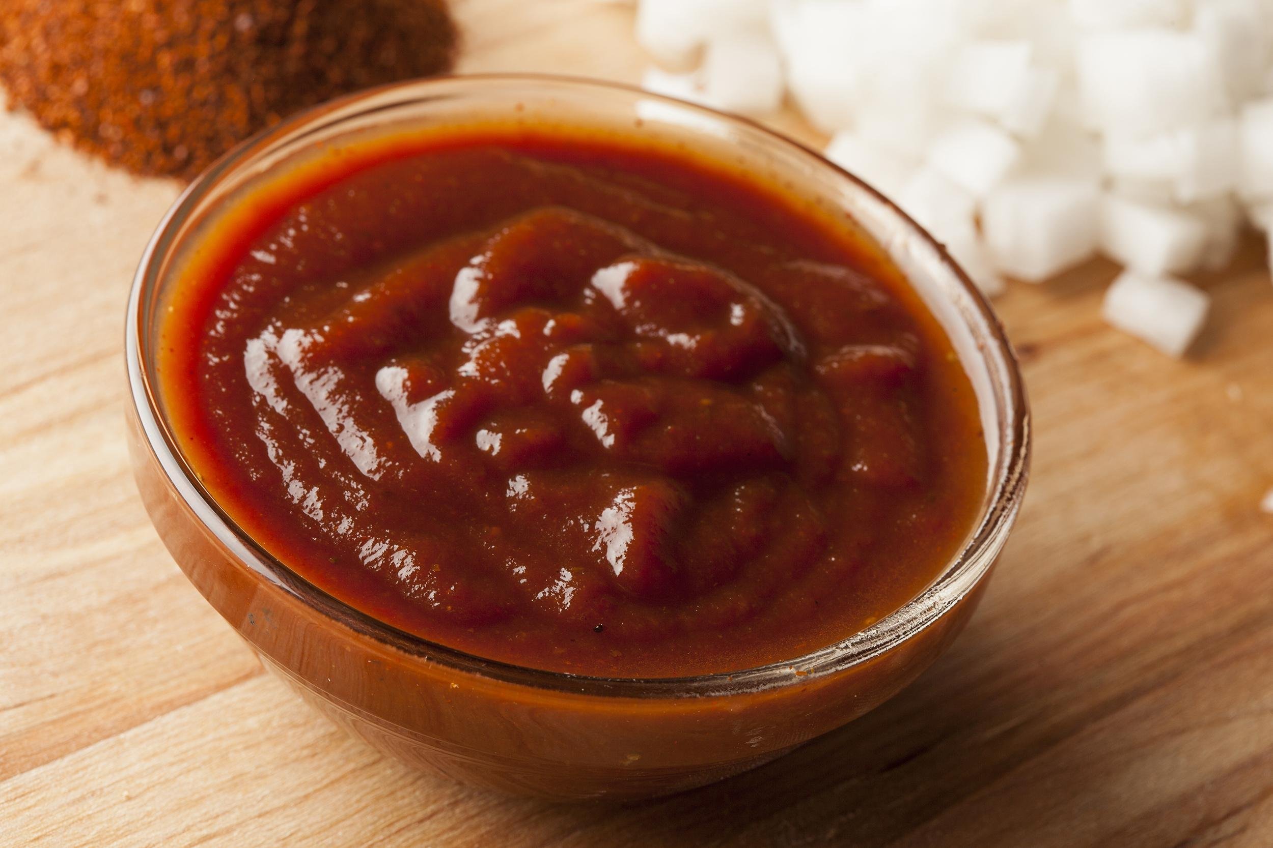 barbecue sauce in dish on table with diced onions in background