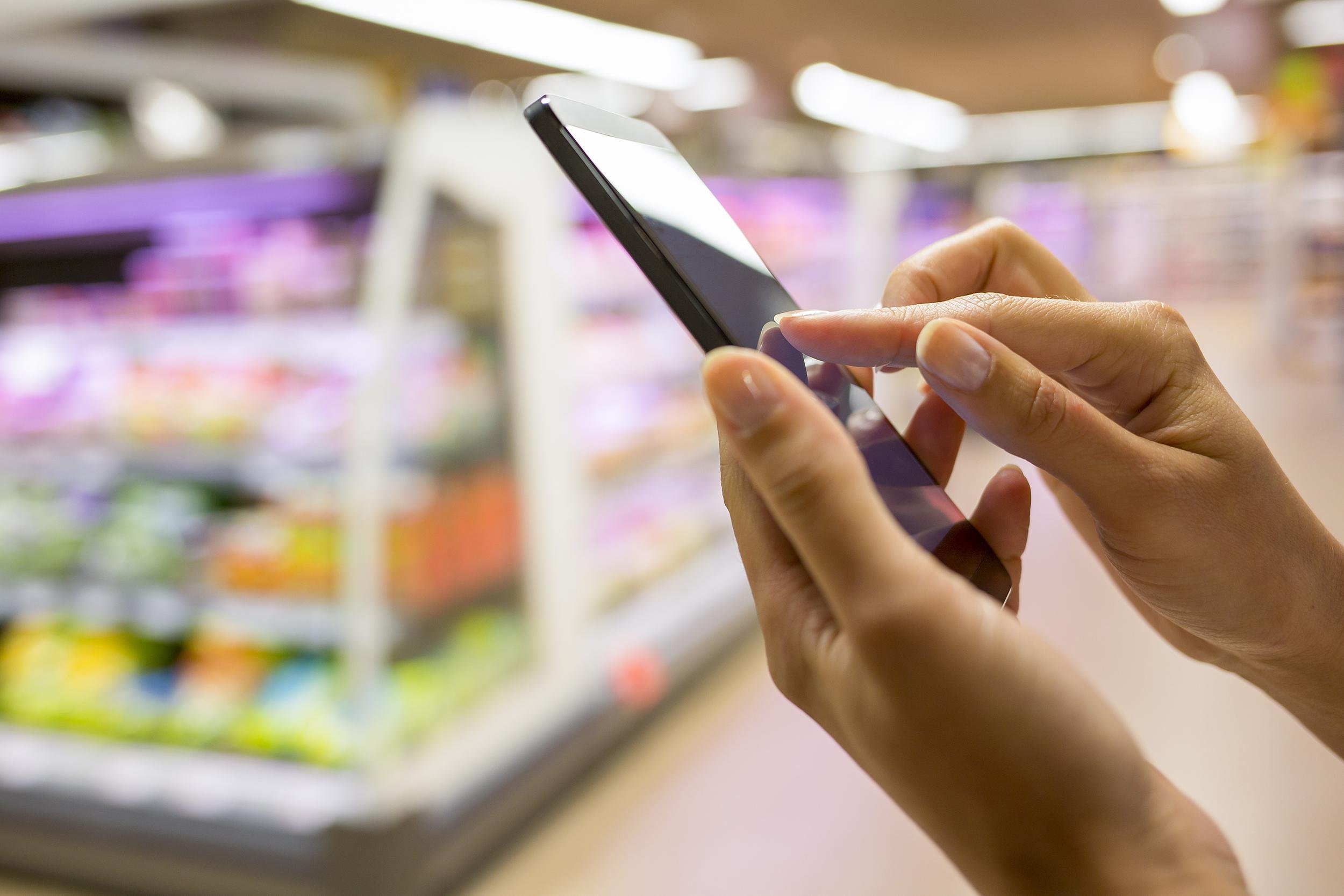 hand with mobile in grocery store