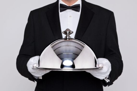 waiter serving a meal under a silver cloche